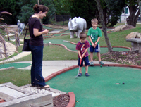 Trying for a hole in one in mini-golf.